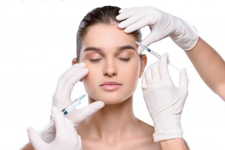 Pretty woman receives botox and filler injections in two sides of the face to compare them