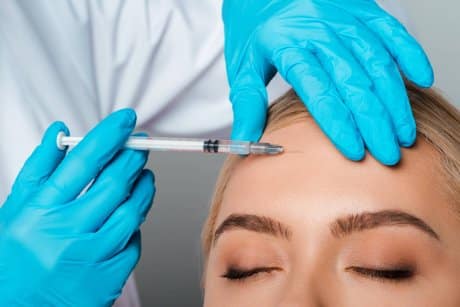 A woman gets botox injection in forehead by doctor to explain the dosage for treatment