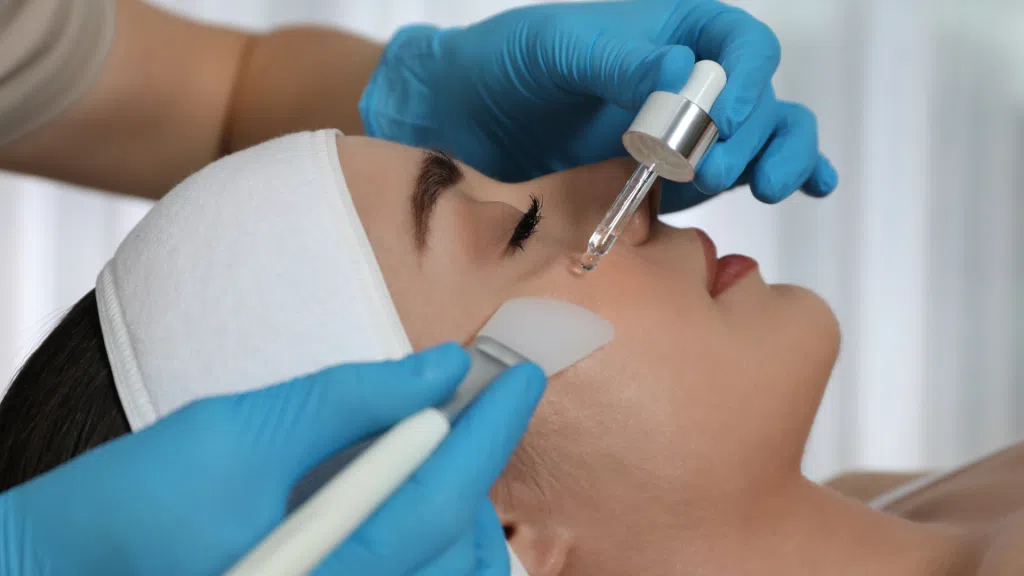 A practitioner applies biorepeel treatment on the patient’s face, spreading it with a specific brush.