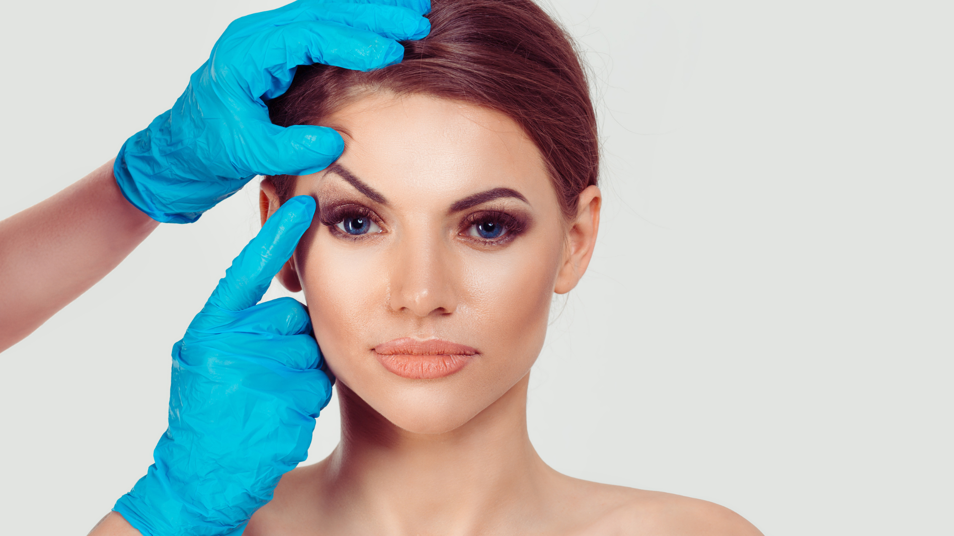 A professional assesses an individual's face for their eyelid lift treatment.