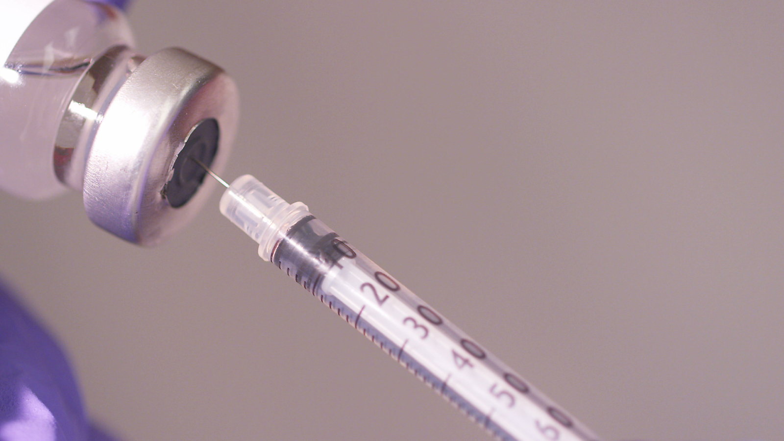 A syringe getting filled with the solution from the vial.