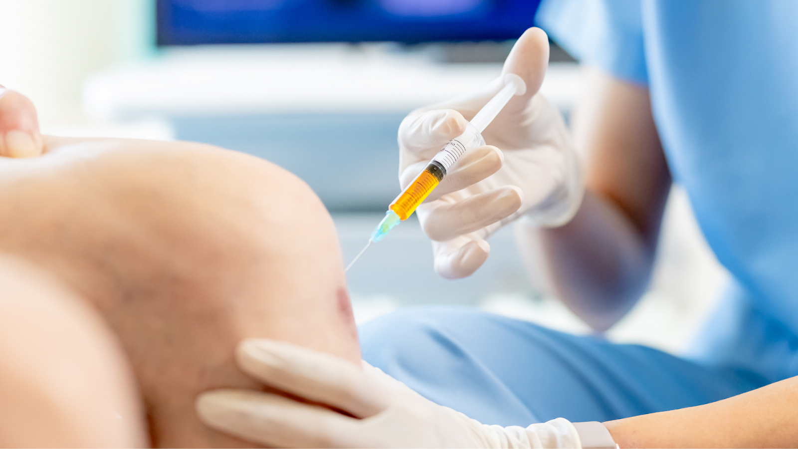 A medical professional injecting a treatment into the knee of a patient.