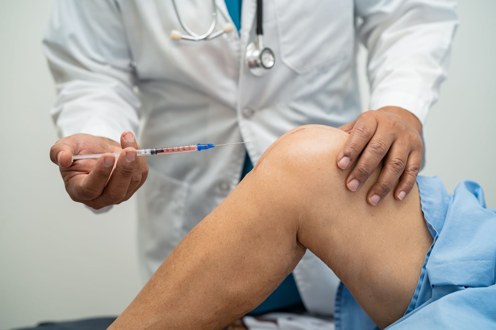 A medical professional administering a knee injection for their patient.