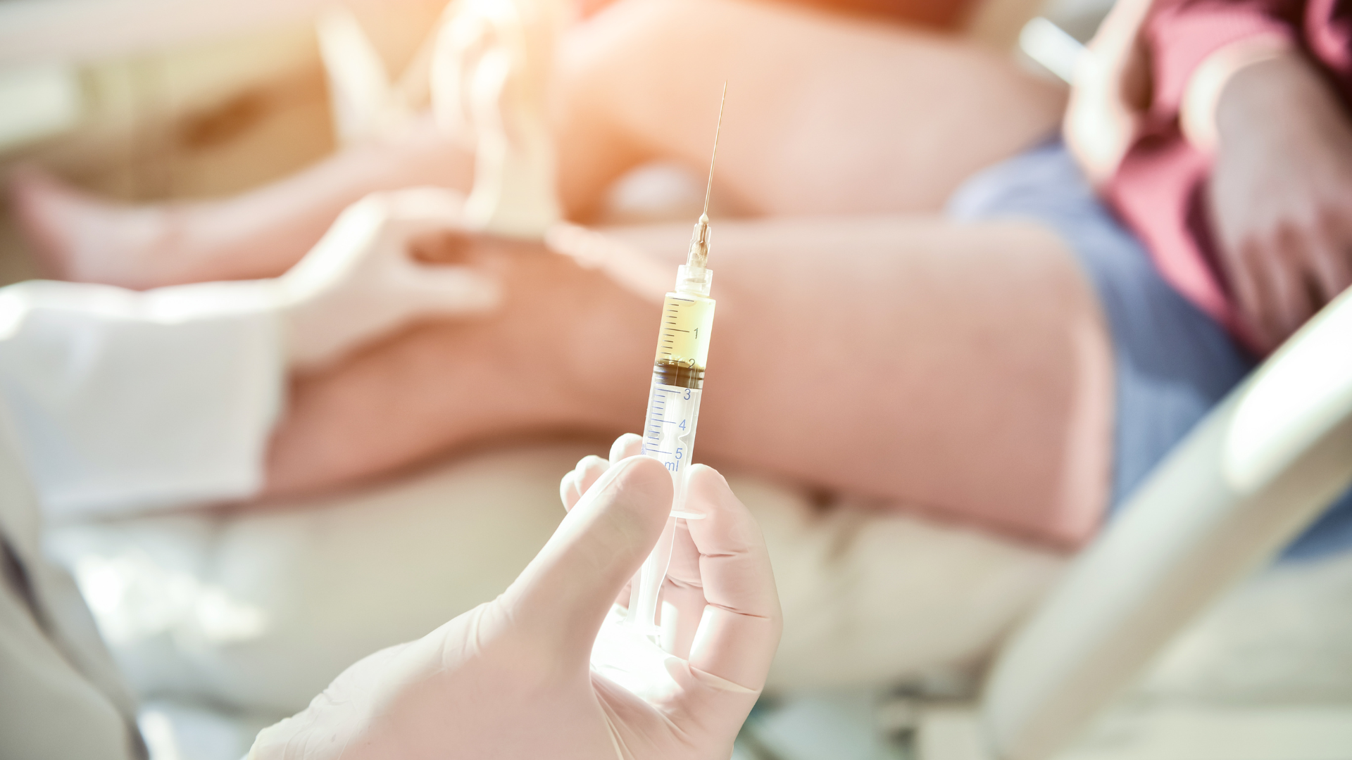 A medical professional preparing to administer a knee injection to the patient.