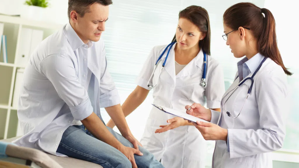 A patient consulting with medical practitioners about their knee pain.