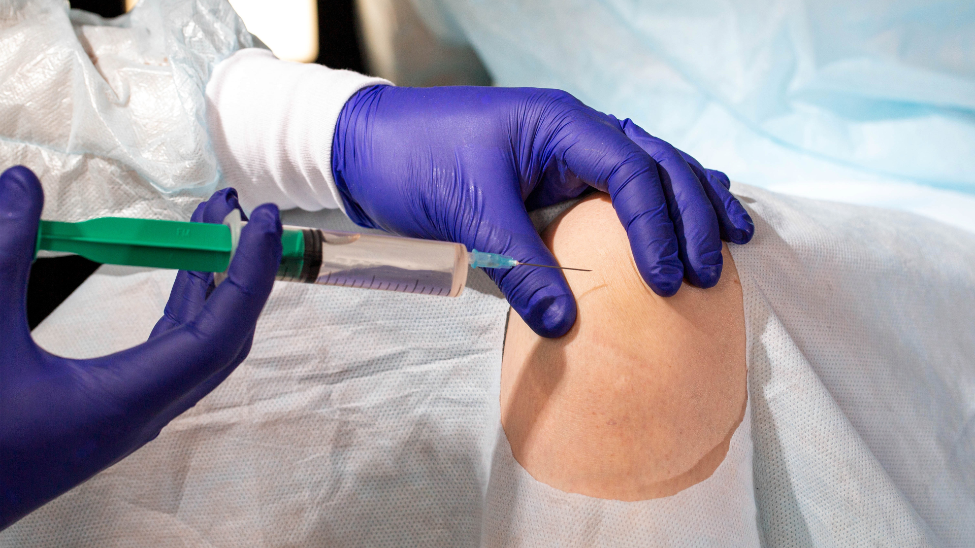 A healthcare provider administering injection into the patient's knee.