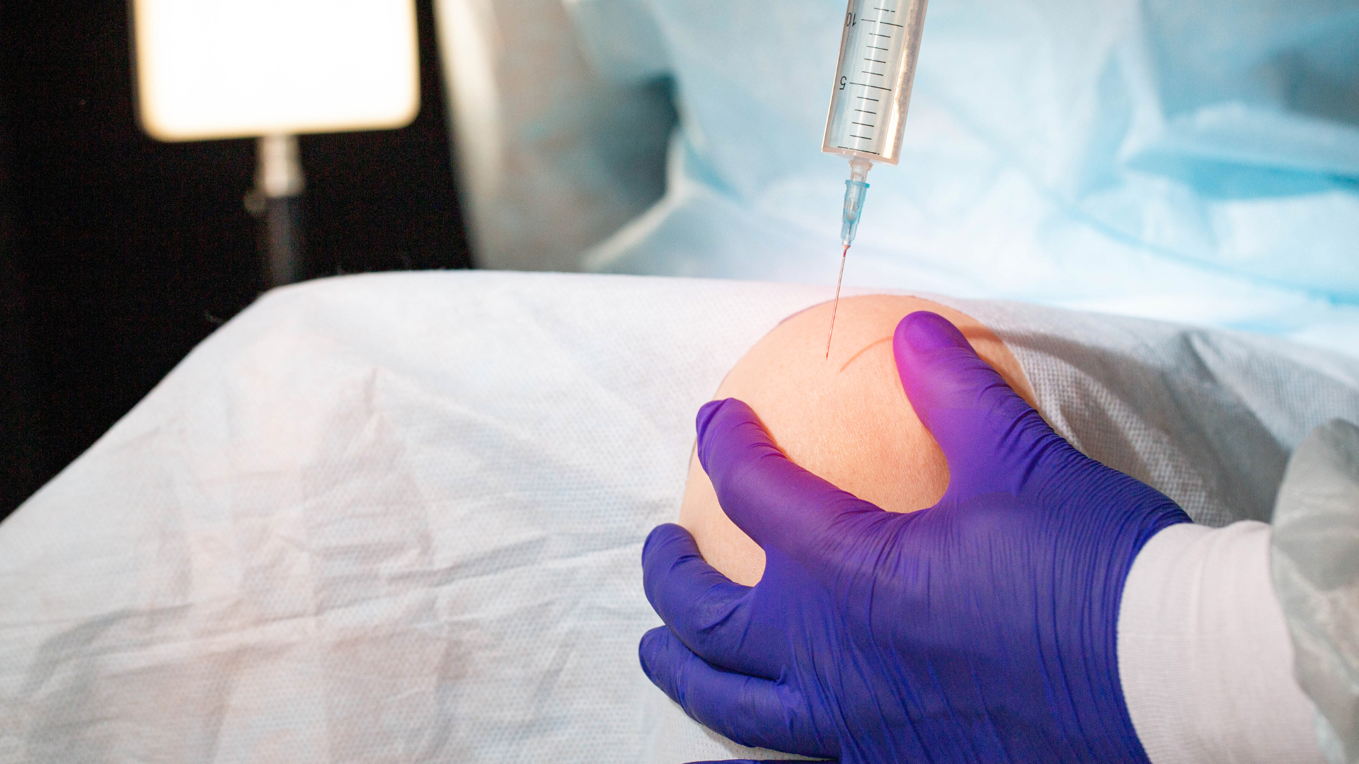 A medical professional administering an injection into the patient's knee.