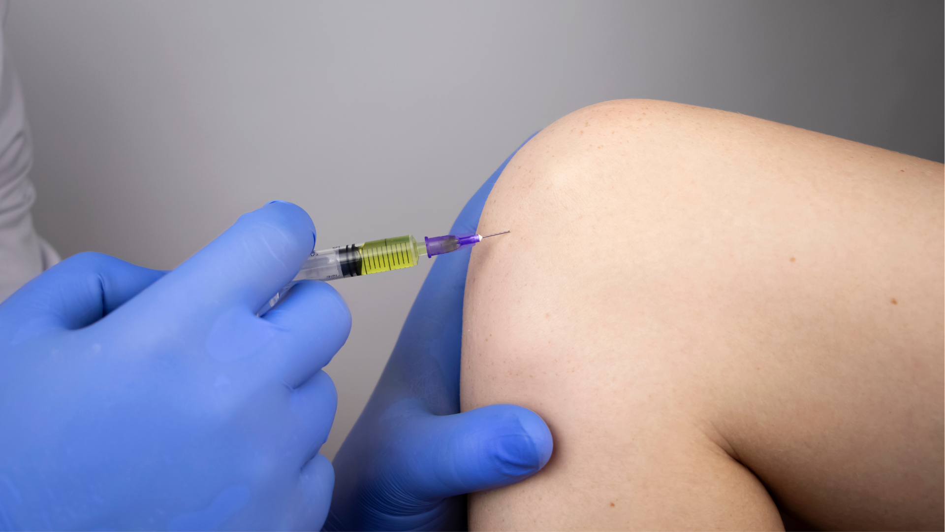 A medical practitioner administering a knee injection to a patient.