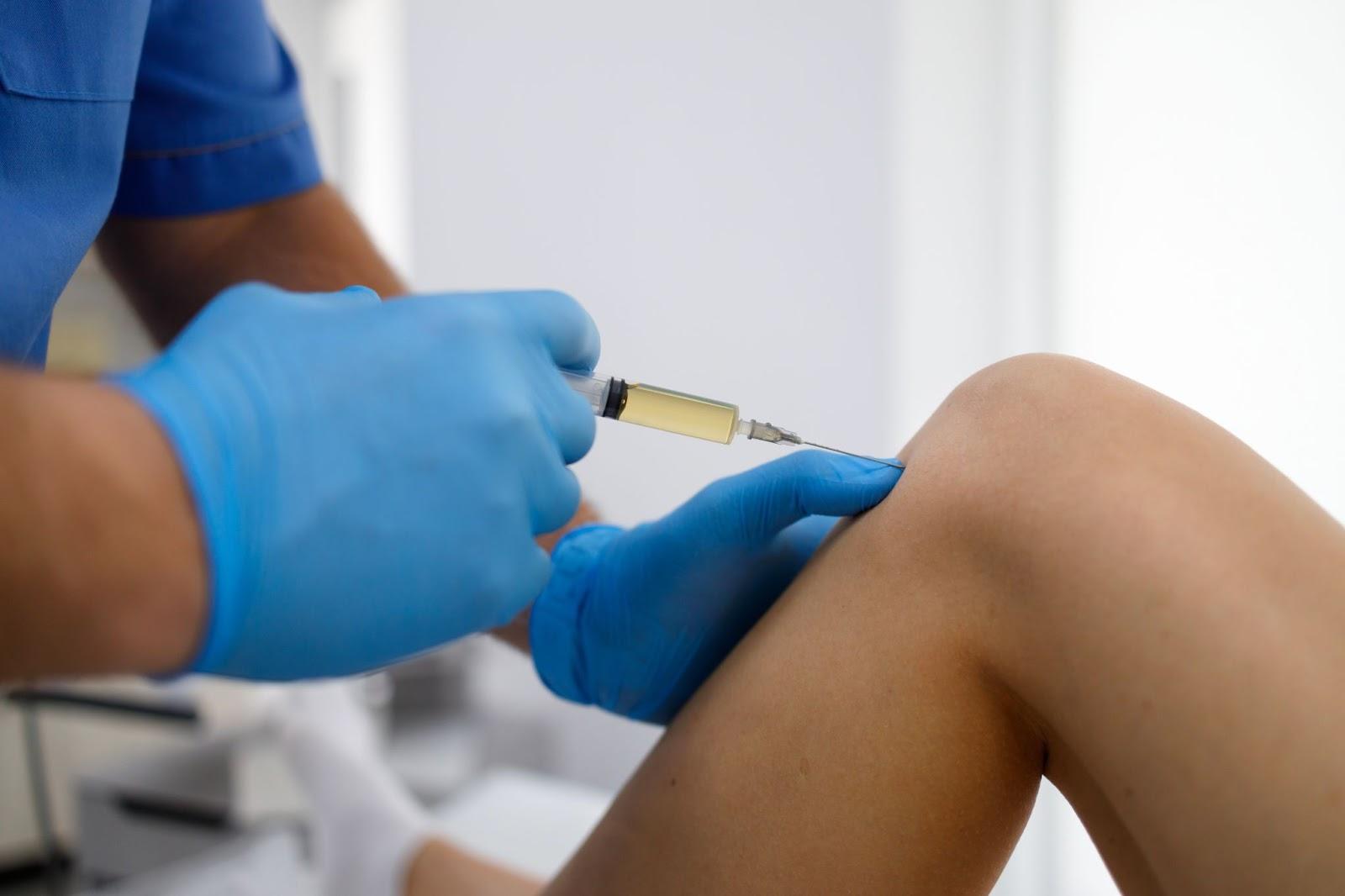 A medical professional administering an injection into the patient's knee joint.