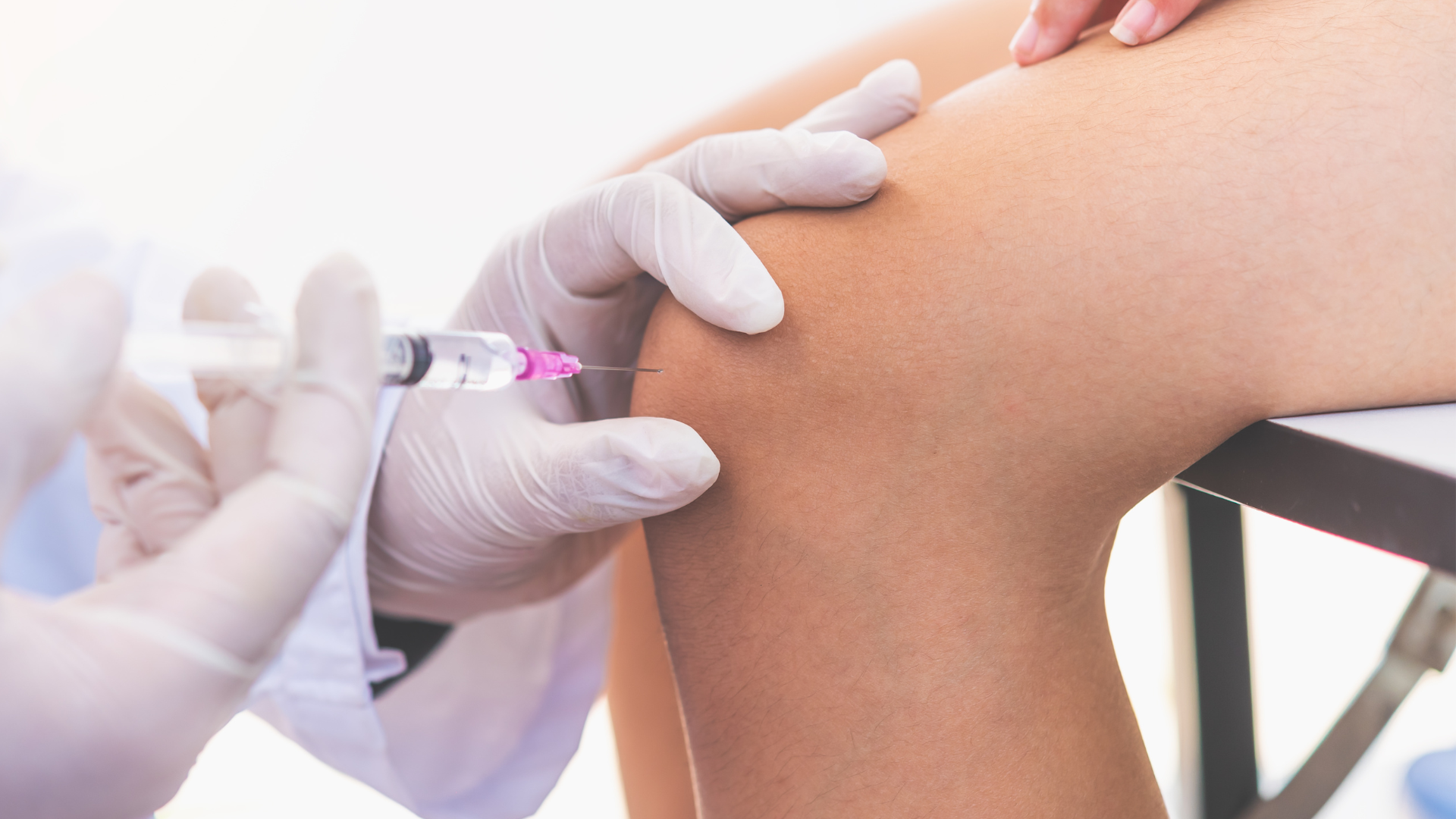 A medical professional administering injection into the patient's knee.