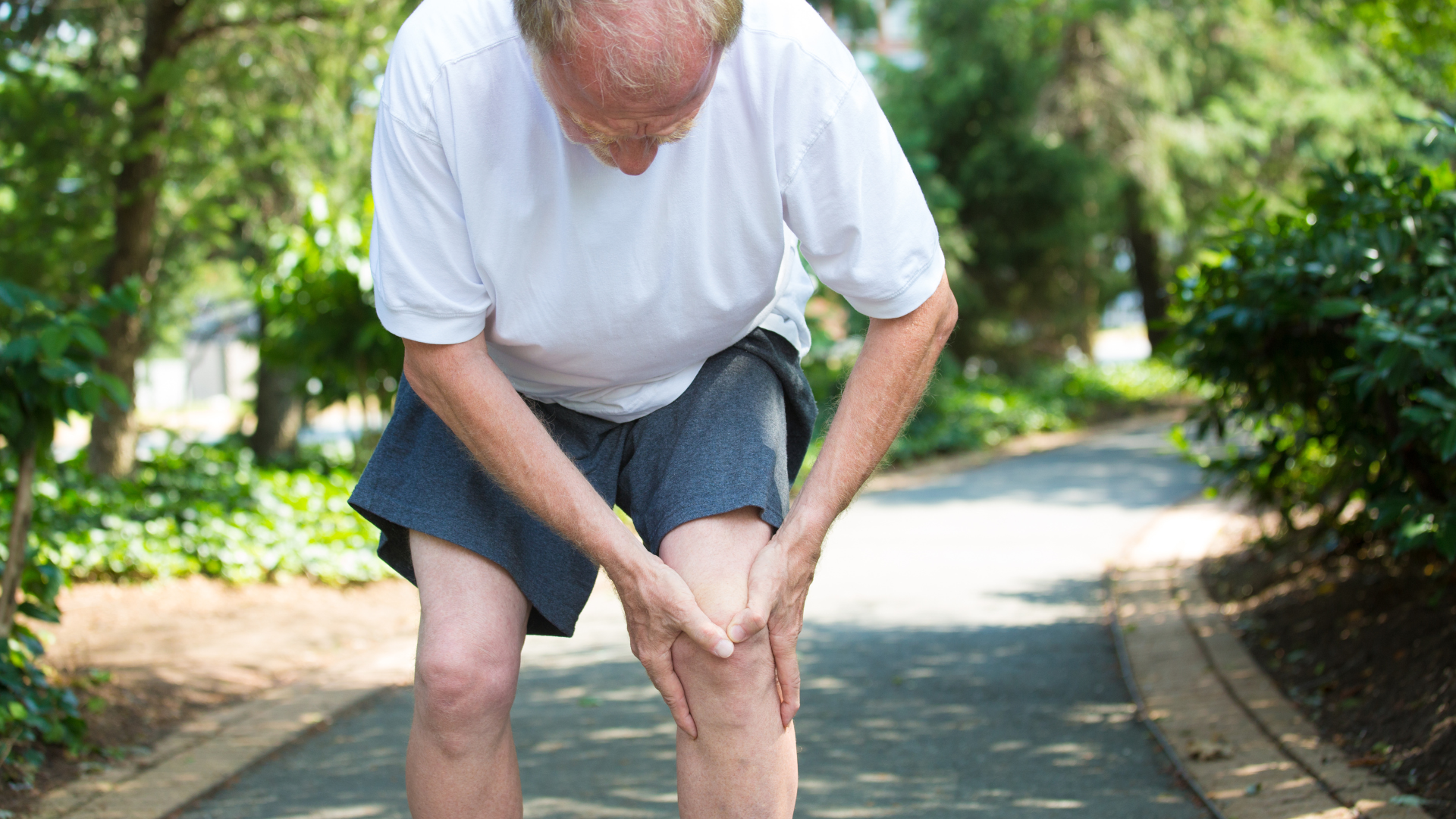 An older individual suffering from knee pain while walking.