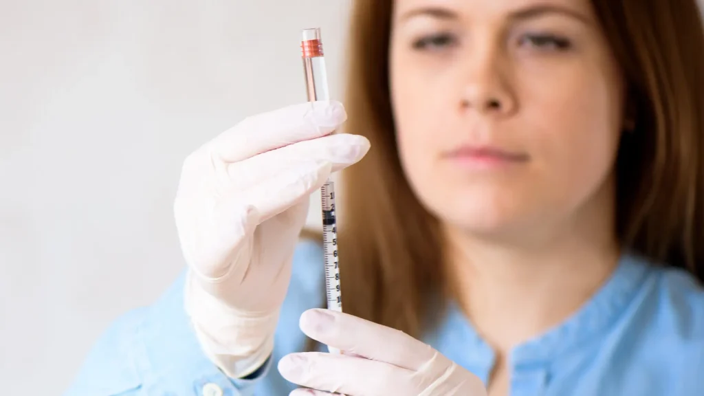 A medical professional transferring the vial's content into the syringe.