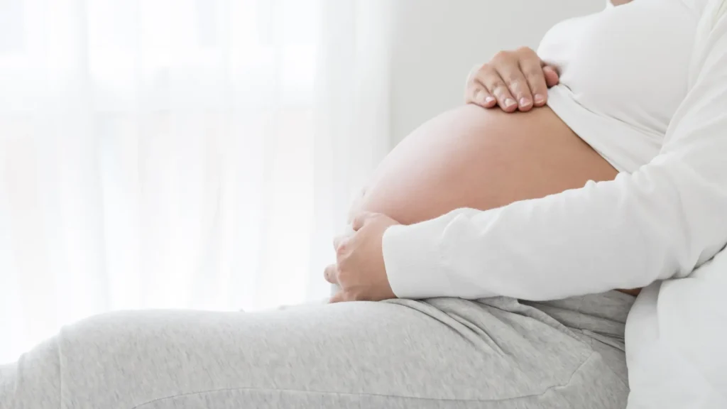 A pregnant individual holding their belly.