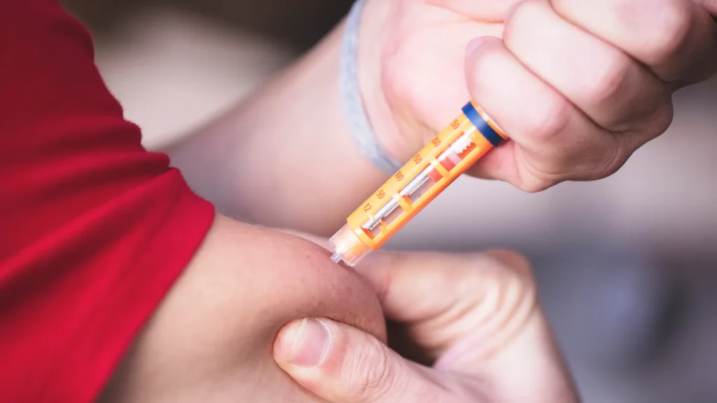 An individual administering an injectable in their upper arm.