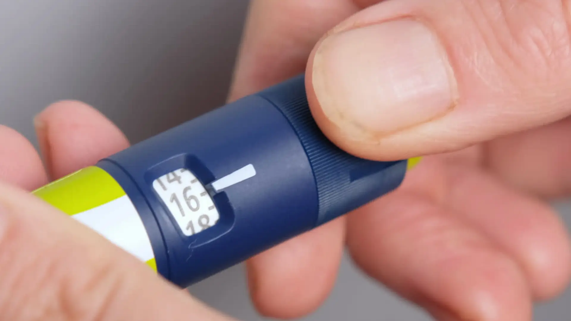 An individual preparing their injectable pen's dosage before injection.