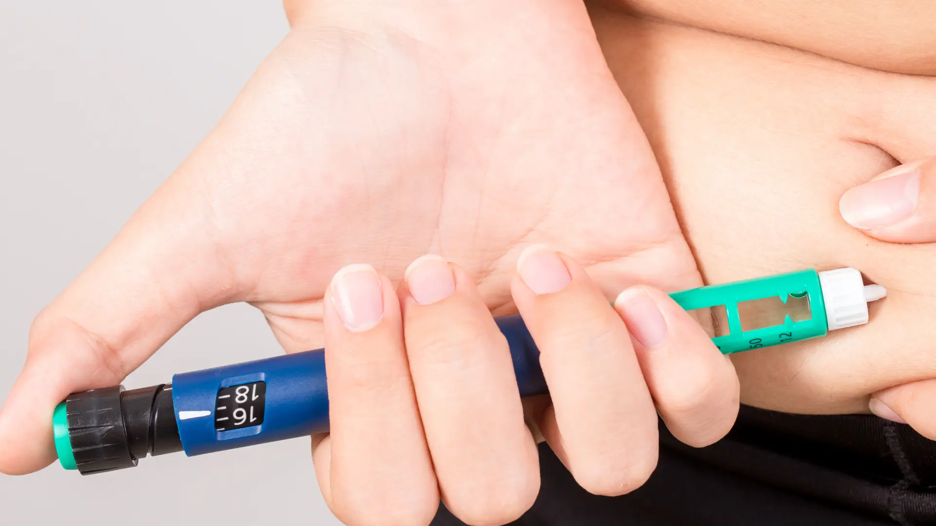 An individual administering a shot on their abdomen.