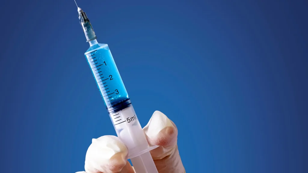 A medical professional holding a medical syringe.