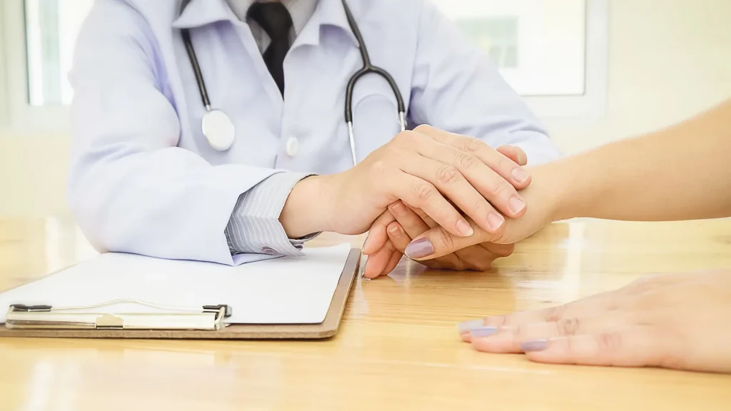 A medical professional holding the patient's hand for support.