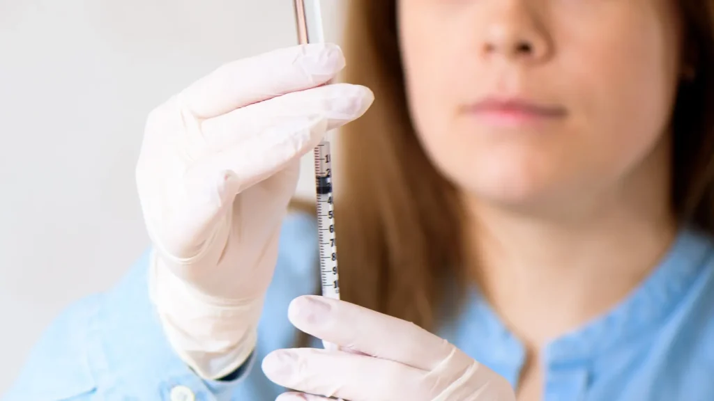 A medical professional transferring the solution into the syringe.