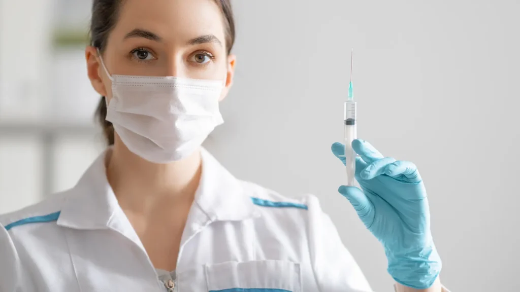 A medical professional holding a medical syringe.