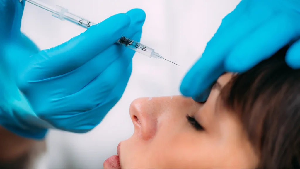 A medical professional administering an injection into a patient's forehead.