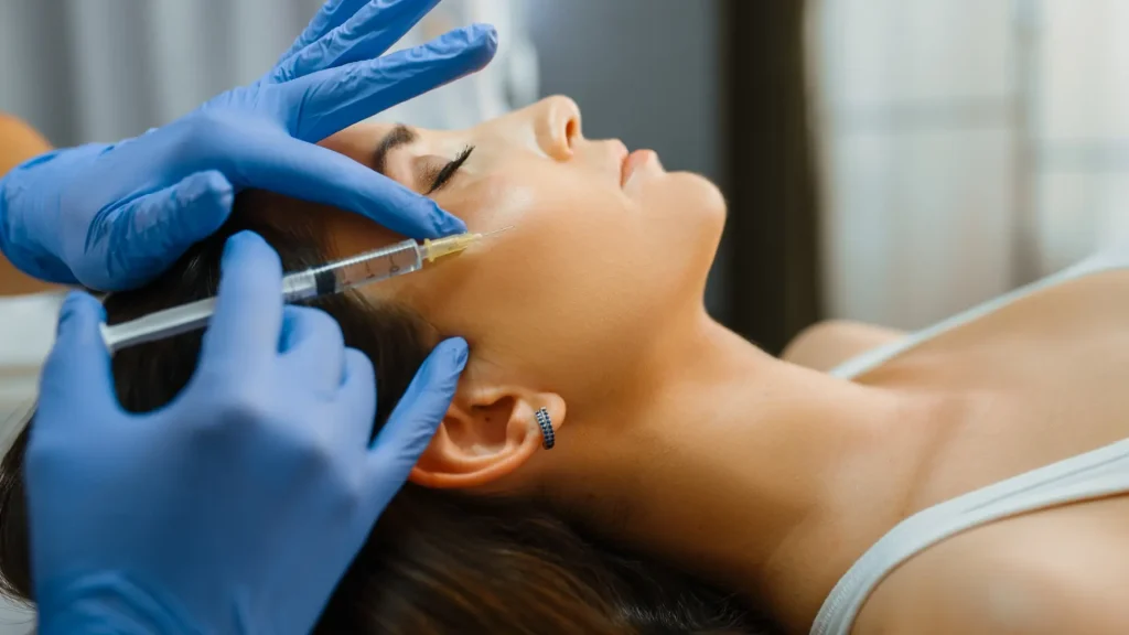 A medical professional administering an injection into patient's mid-face region.