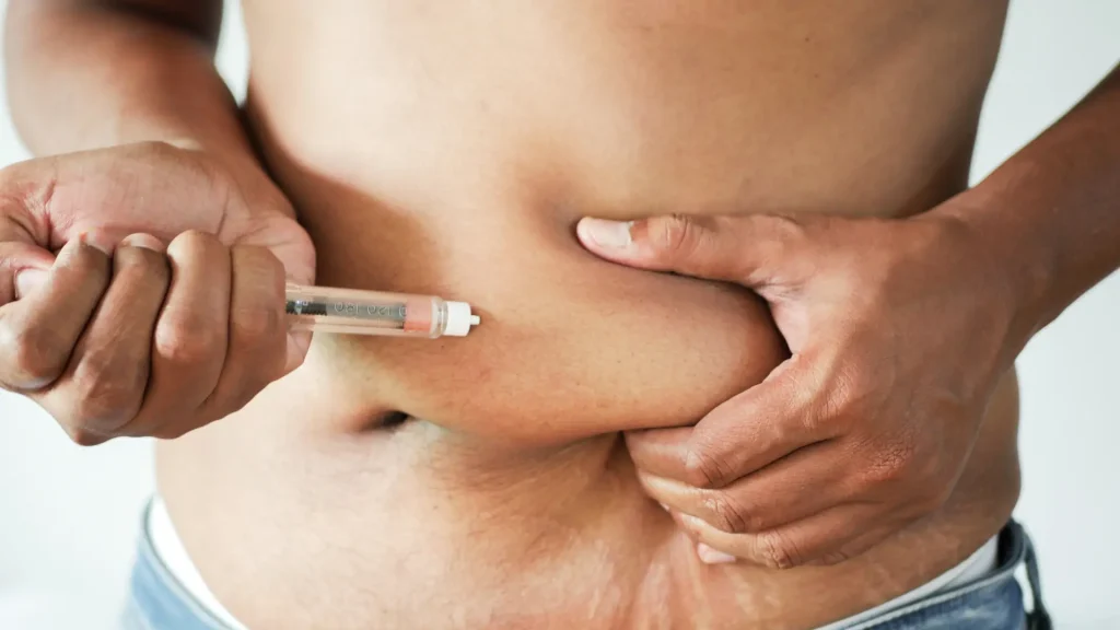 An individual administering an injectable pen injection into their abdomen.