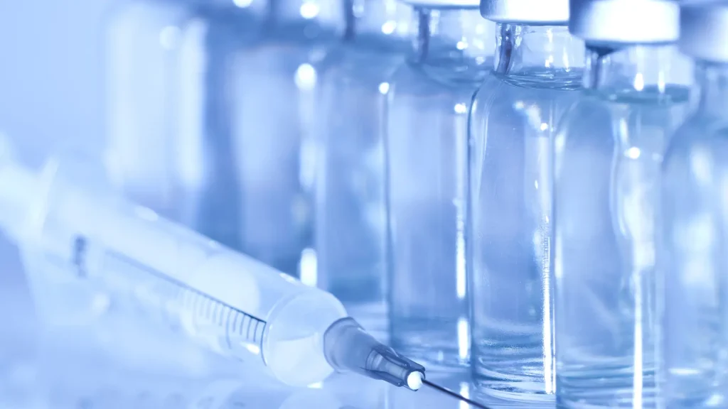 Solution vials lined up with a medical syringe on the side.
