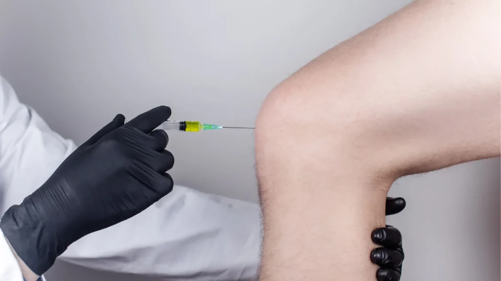 A medical professional administering a knee injection.