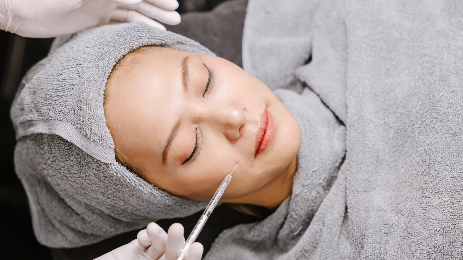 An individual receiving an injection into their mid-face region.