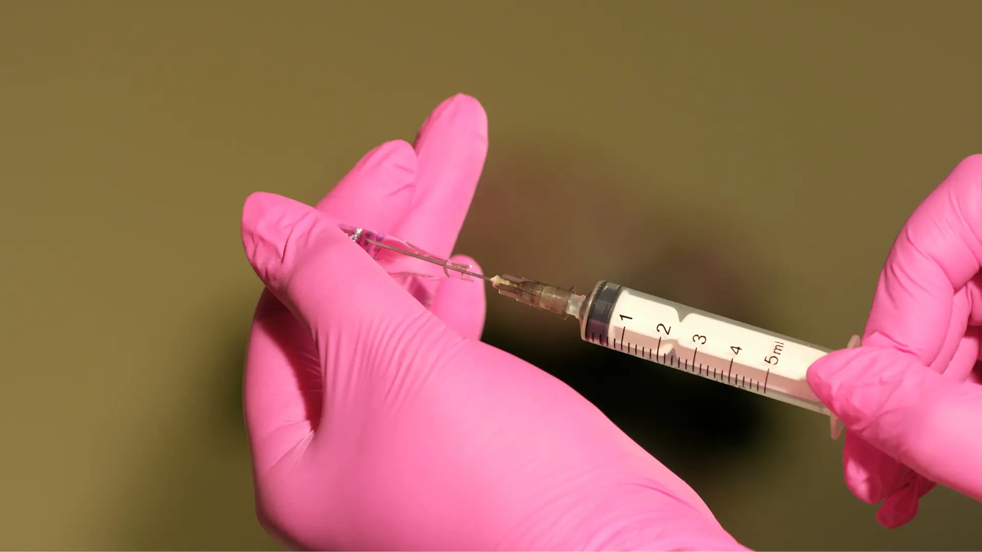 A medical professional preparing a syringe for injection.
