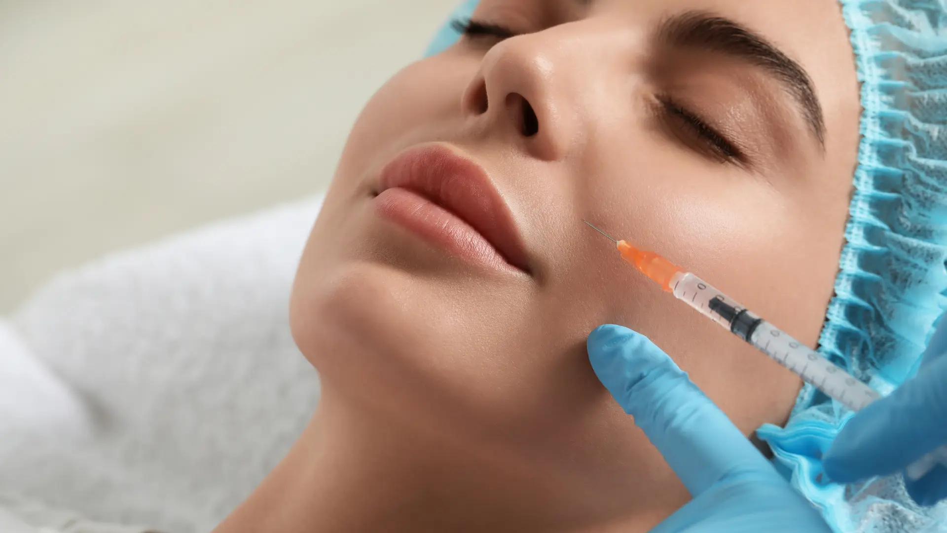 An individual receiving injection into a patient's facial region.