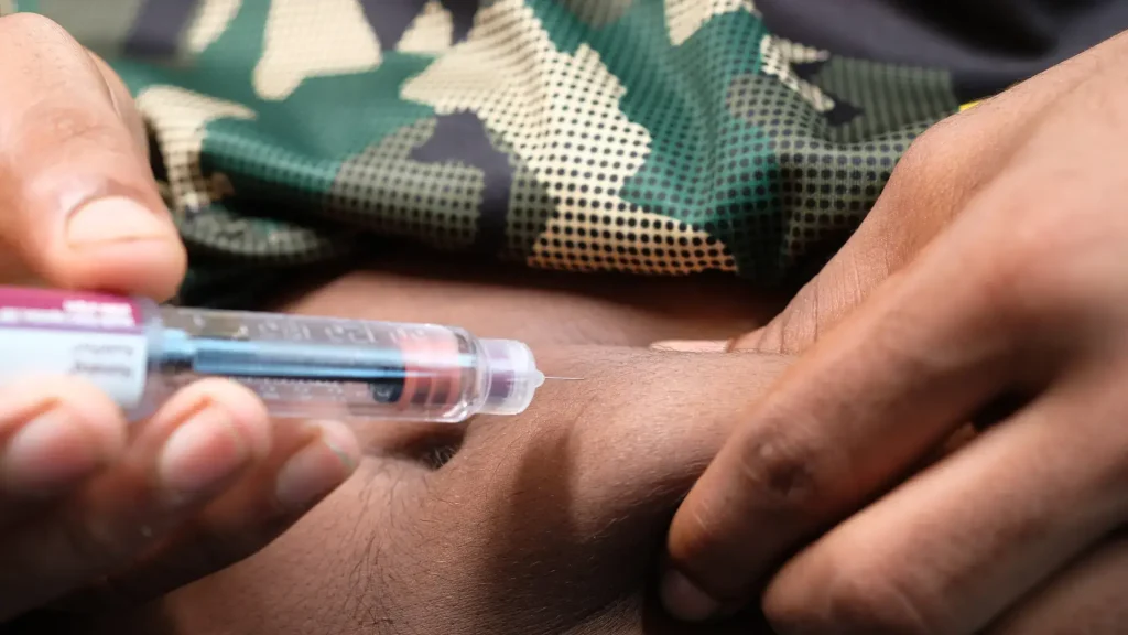 An individual administering an injection into their abdomen.