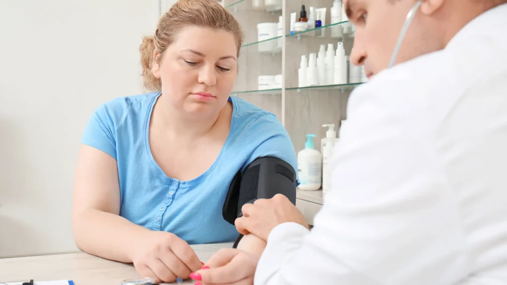 An individual consulting a doctor and getting their blood pressure checked.
