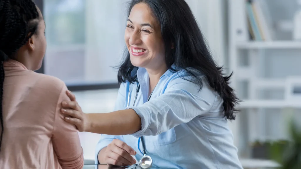 A medical professional assuring a patient during their consultation.