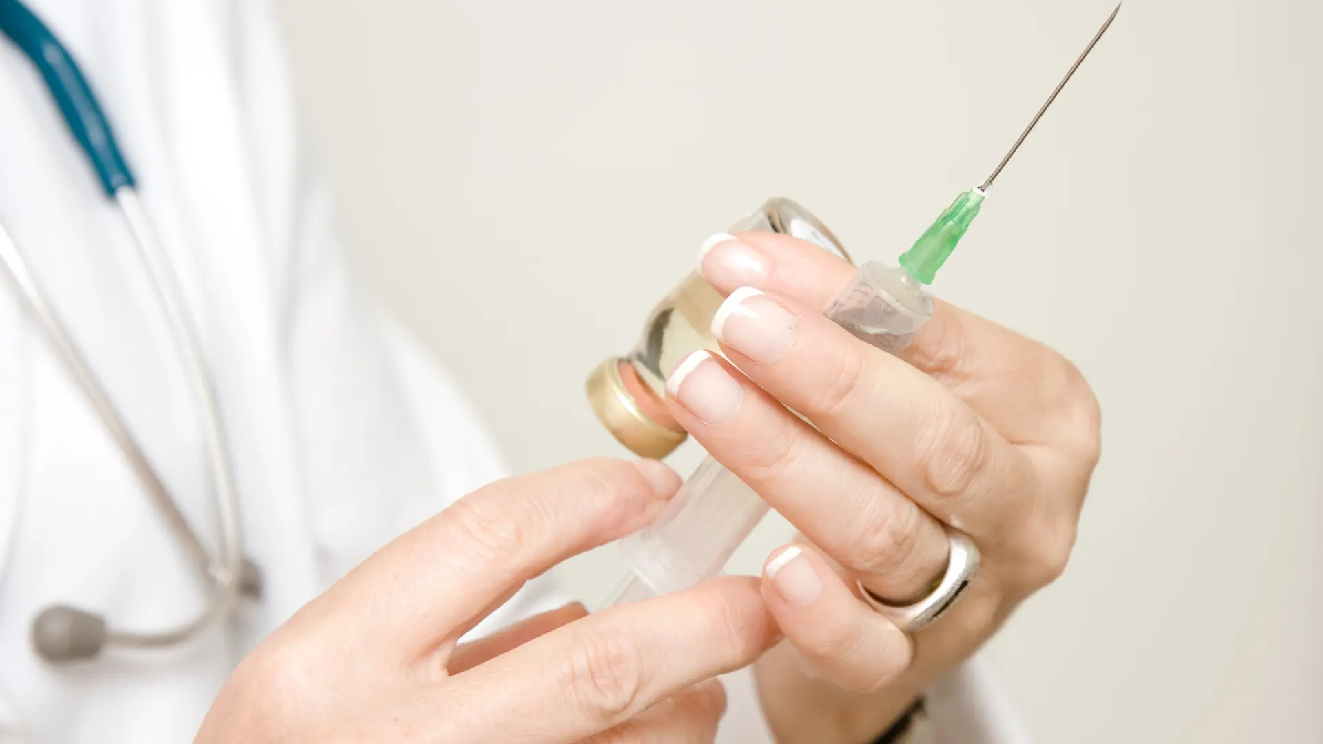 A medical professional preparing the syringe for treatment.