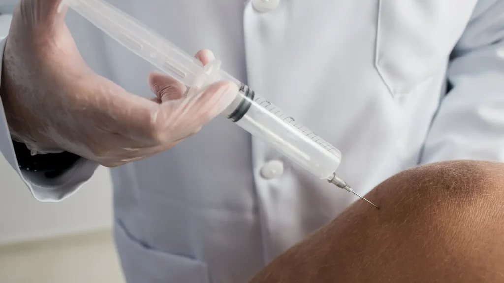 A medical professional administering a knee injection.