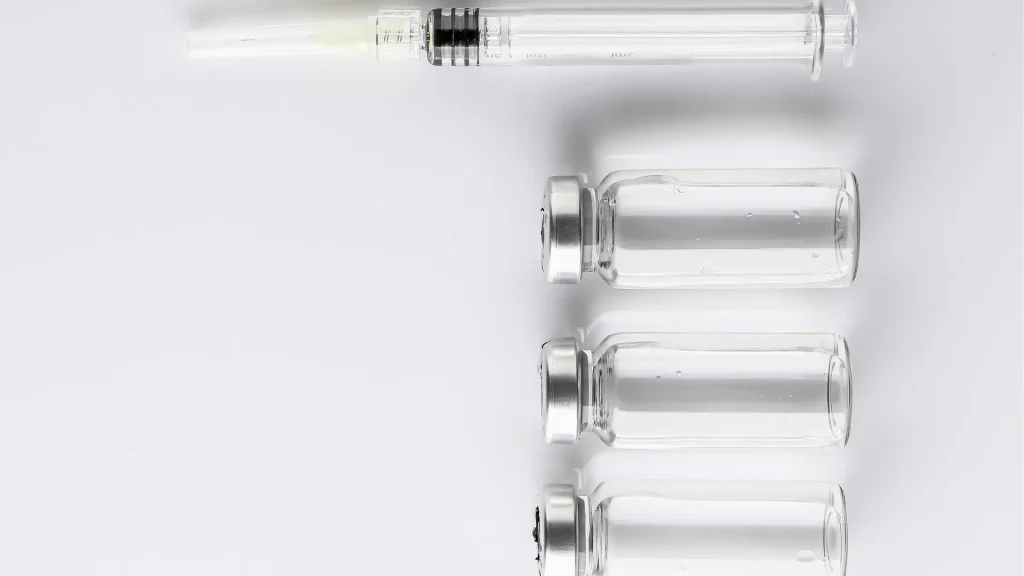 A medical syringe lined up with solution vials.