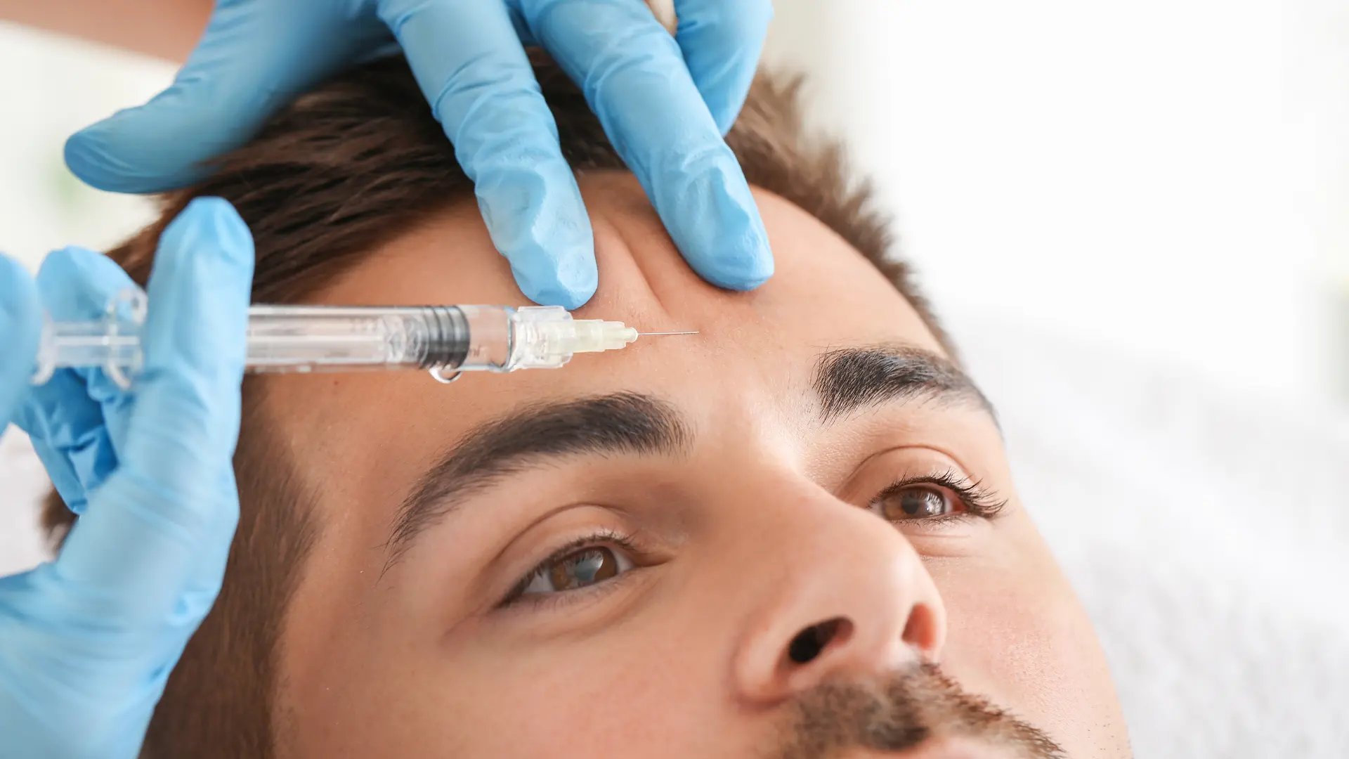 An individual receiving an injection into their '11' line on the forehead.