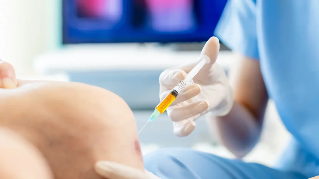 A practitioner administering a knee injection.