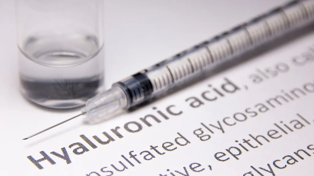 A close up shot of hyaluronic acid definition and a medical syringe.