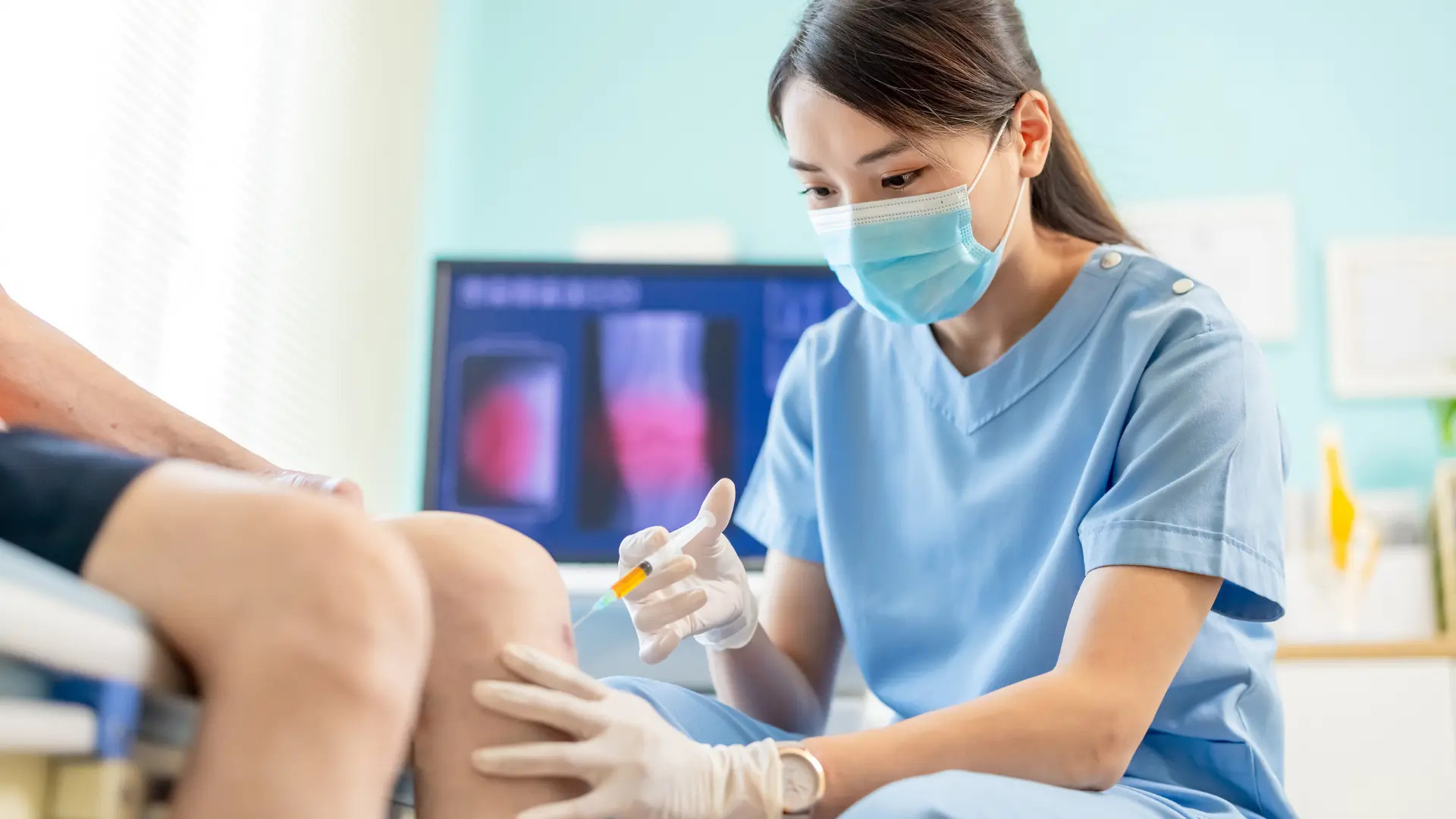A medical professional administering a knee injection.