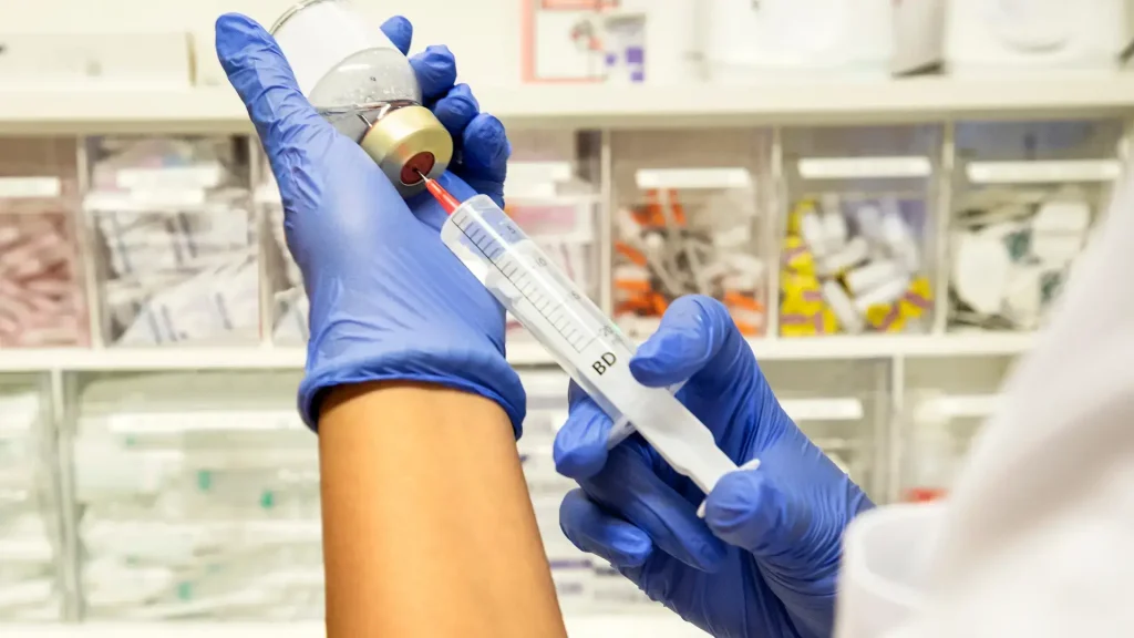 A close-up shot of a medical professional transferring the solution into the injection.