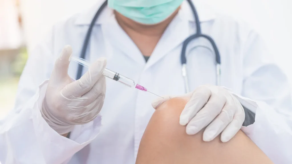 A medical professional administering a knee injection.