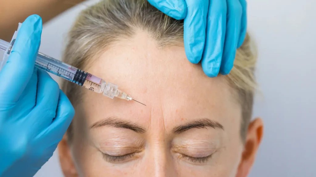 A medical professional administering an injection into the patient's forehead.