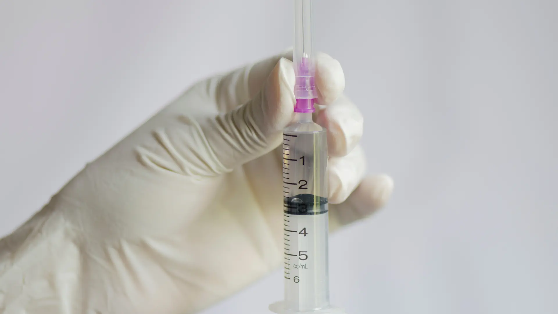 A close-up shot of a medical professional holding a medical syringe.