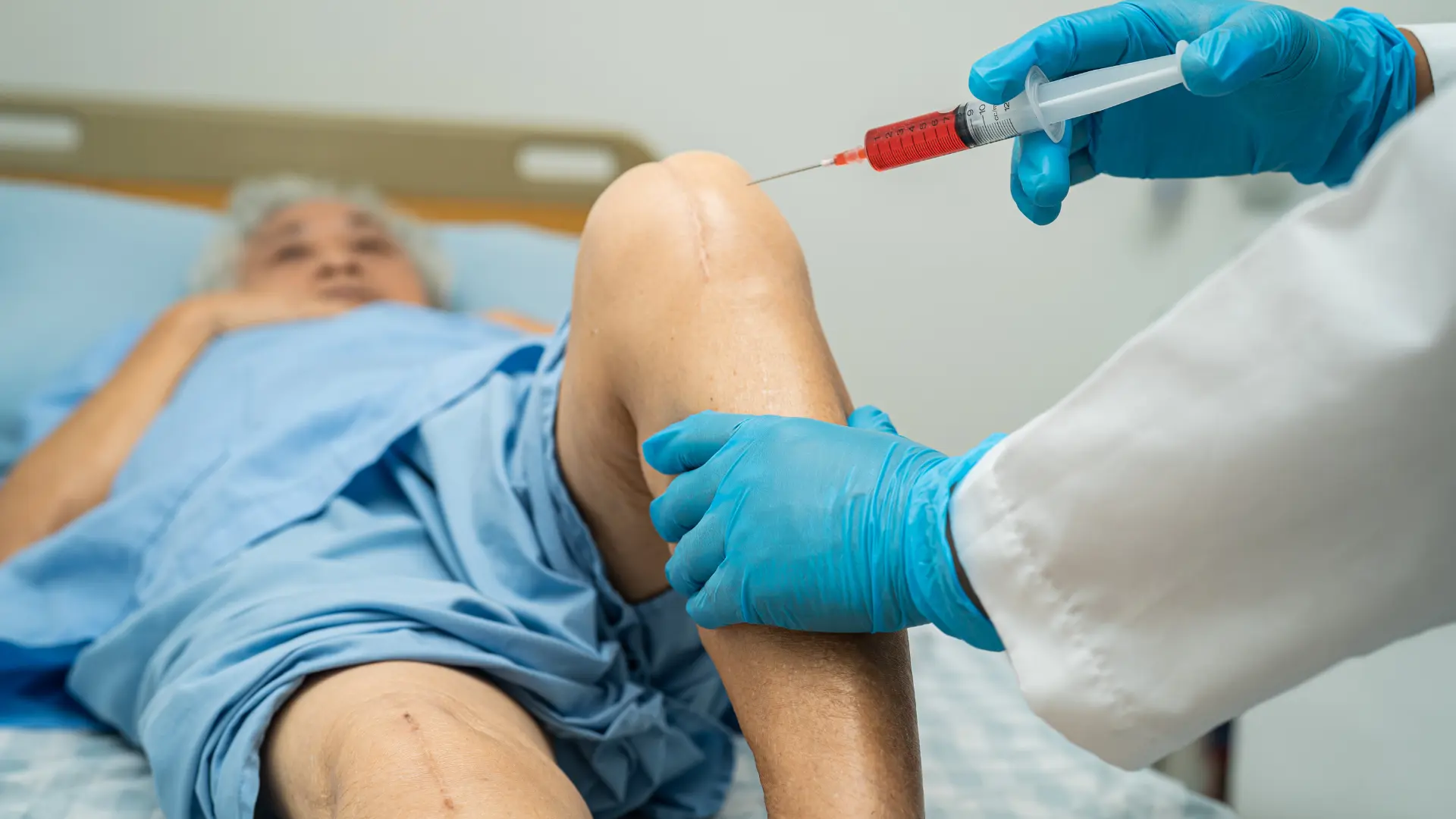A medical professional administering a patient's knee injection.