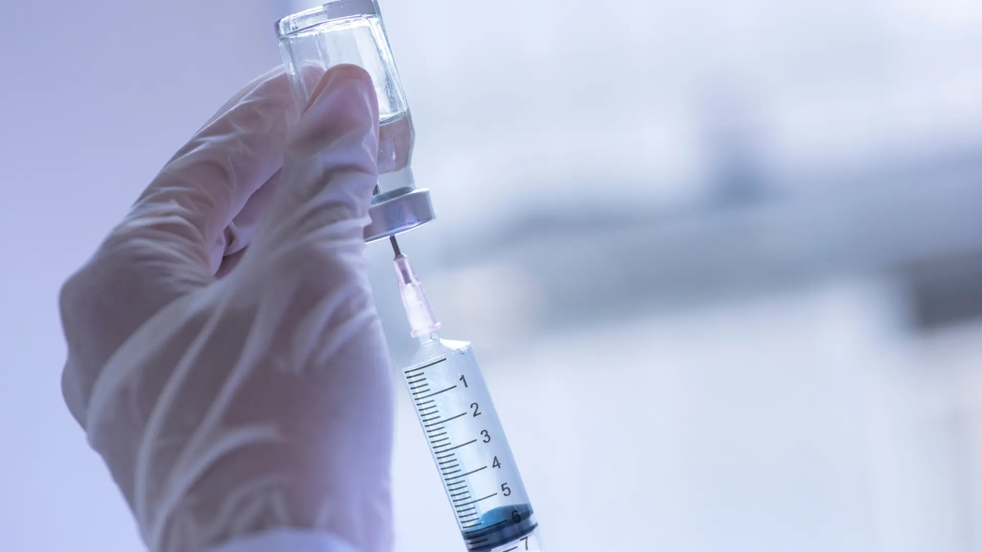 A medical professional transferring the vial's solution into the injection.