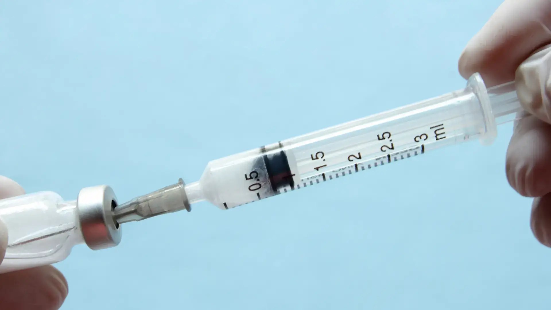 A close-up shot of a medical professional transferring the solution into the syringe.