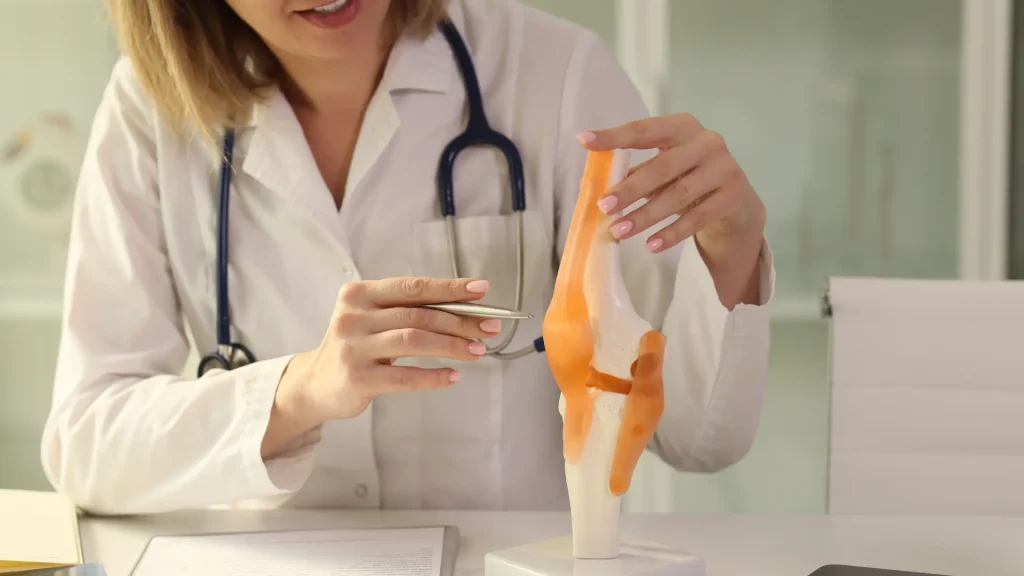 A medical professional explaining the knee region and treatment procedure.